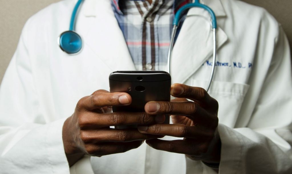 A doctor wearing stethoscope and using his mobile
