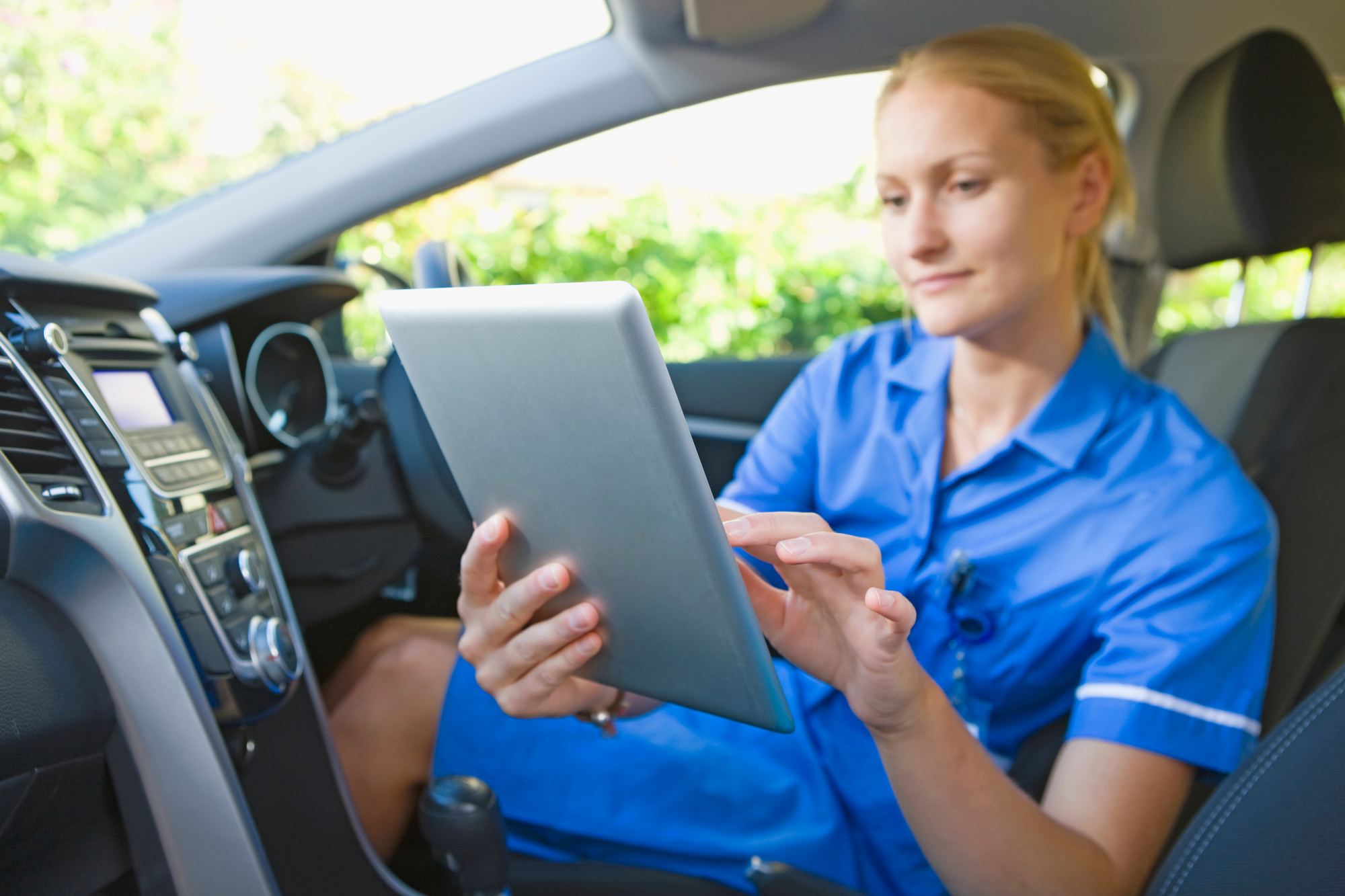 A community nurse looking at tablet in her car